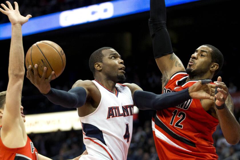 Hawks forward Paul Millsap (4) goes up for a shot between Trail Blazers forward LaMarcus Aldridge (12) and center Meyers Leonard in the first half Friday night.