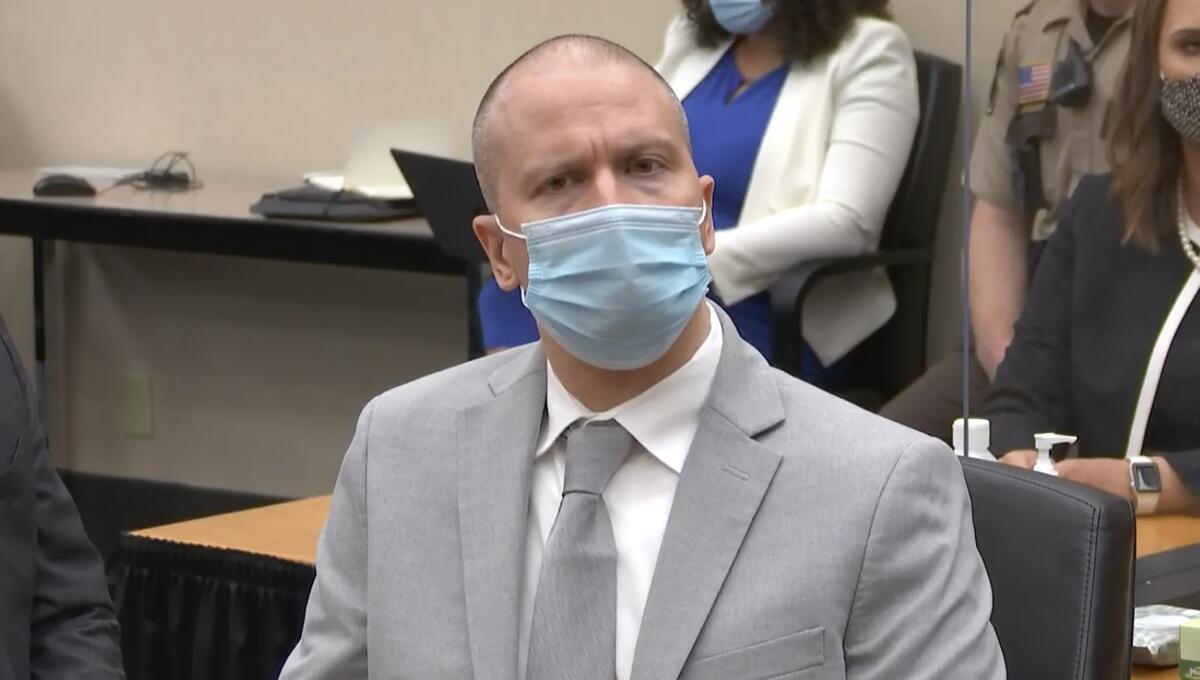 Derek Chauvin sits in court in gray mask and business suit.