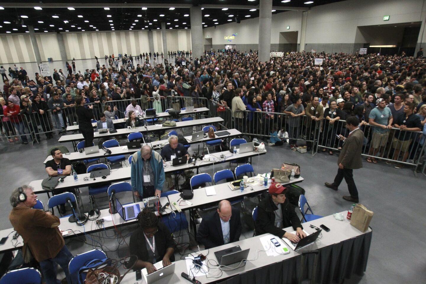 People surround the media work area as they watch Democratic presidential candidate Bernie Sanders.