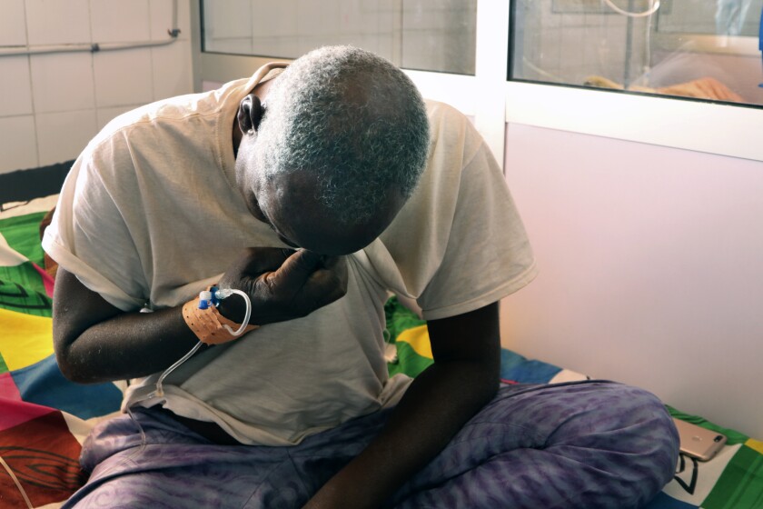 Ousseni Yanogo, 63, sits on his bed at Ouagadougou's Bogodogo Medical Teaching Hospital Thursday Feb. 4, 2021. Yanogo contracted COVID-19 at his 6-year-old grand-daughter's birthday. Since November, the conflict-riddled West African nation of Burkina Faso faces a much deadlier second coronavirus wave than the first and health officials worry a lack of knowledge and adherence to coronavirus measures is making it hard to rein in. (AP Photo/Sam Mednick)