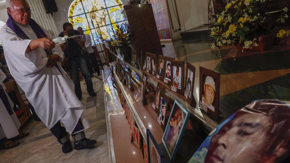 A Catholic priest blesses photos of victims of killings during a Mass in Quezon City, east of Manila, Philippines, on Oct. 31, 2017.