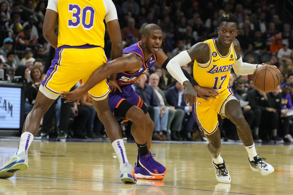 Lakers guard Dennis Schroder drives past Phoenix Suns guard Chris Paul with Lakers center Damian Jones setting a pick.