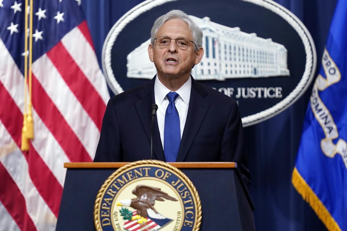 Atty. Gen. Merrick Garland speaking from a lectern with a Department of Justice seal, in front of U.S. and other flags