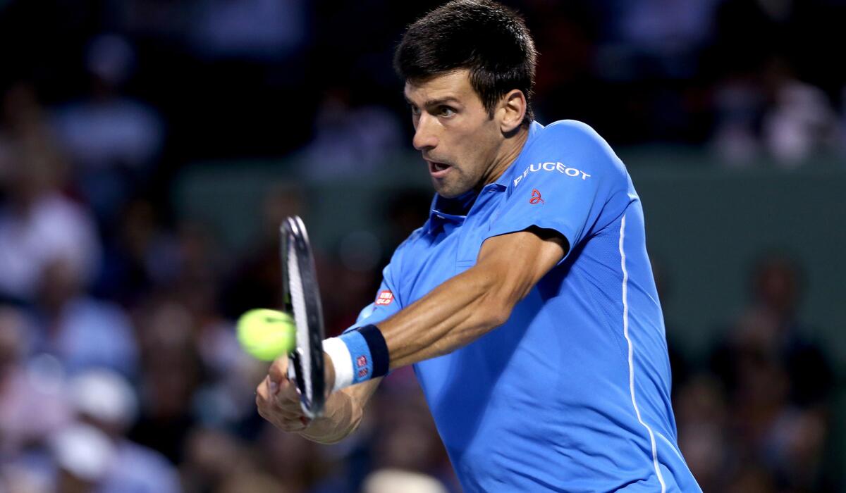 Novak Djokovic returns a shot against John Isner during a semifinal match at the Miami Open on Friday.