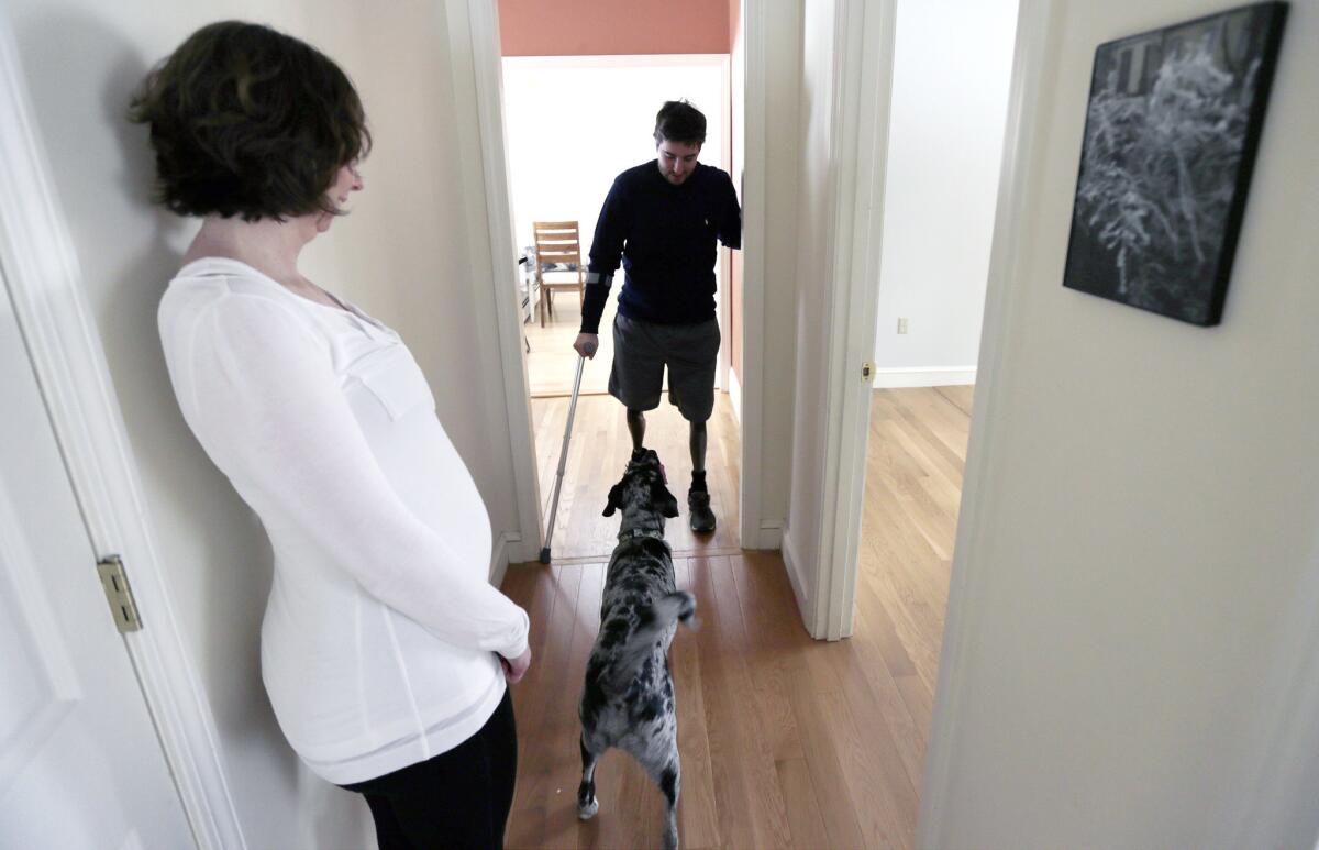 Jeff Bauman talks to his dog Bandit as his fiancee Erin Hurley watches at their home in Carlisle, Mass.