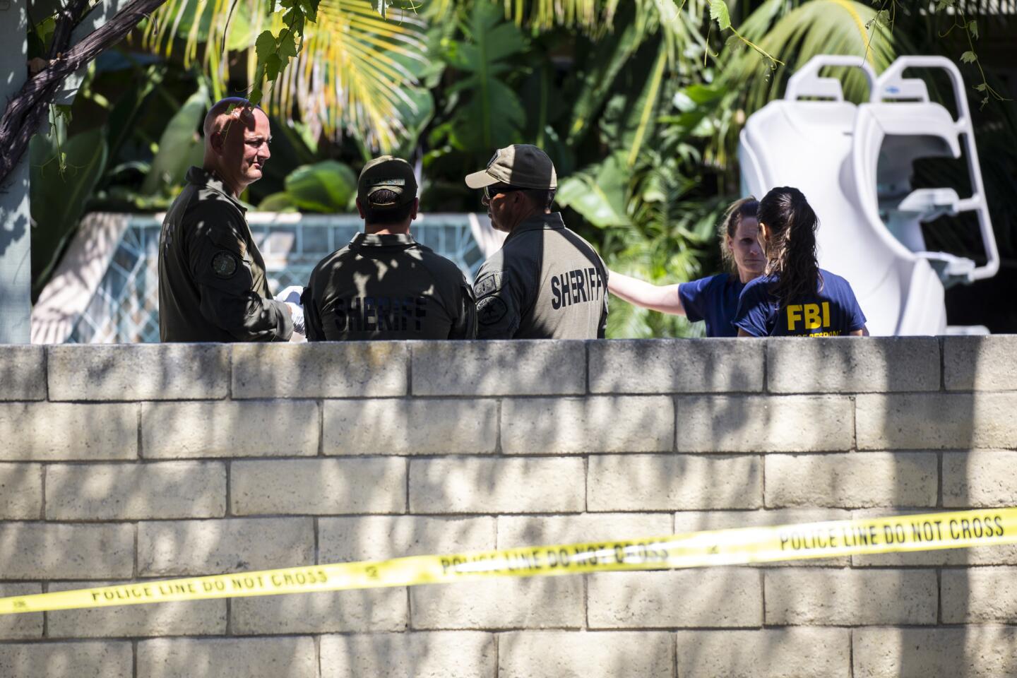 Law enforcement officials search a Long Beach property in connection with the Aliso Viejo explosion.