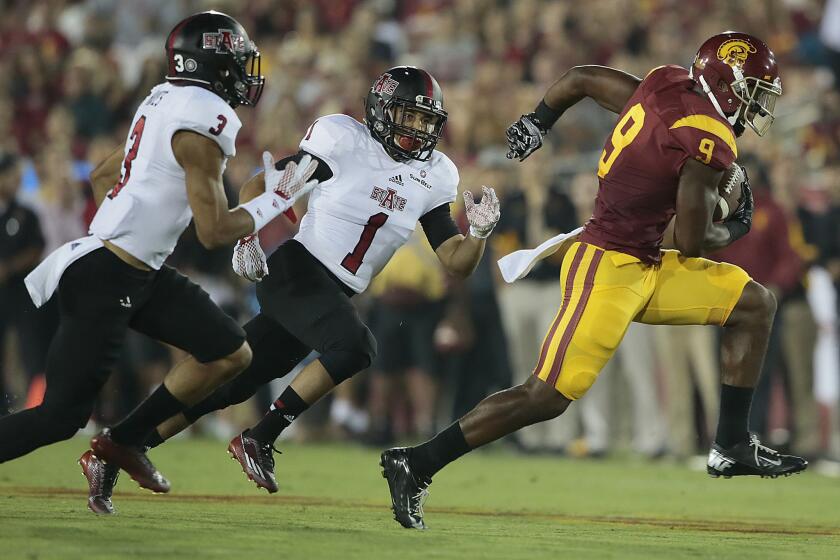 USC receiver JuJu Smith-Schuster speeds past Arkansas State defenders Rocky Hayes (3) and Blaise Taylor (1) for a 61-yard touchdown pass play in the first quarter Saturday night at the Coliseum.
