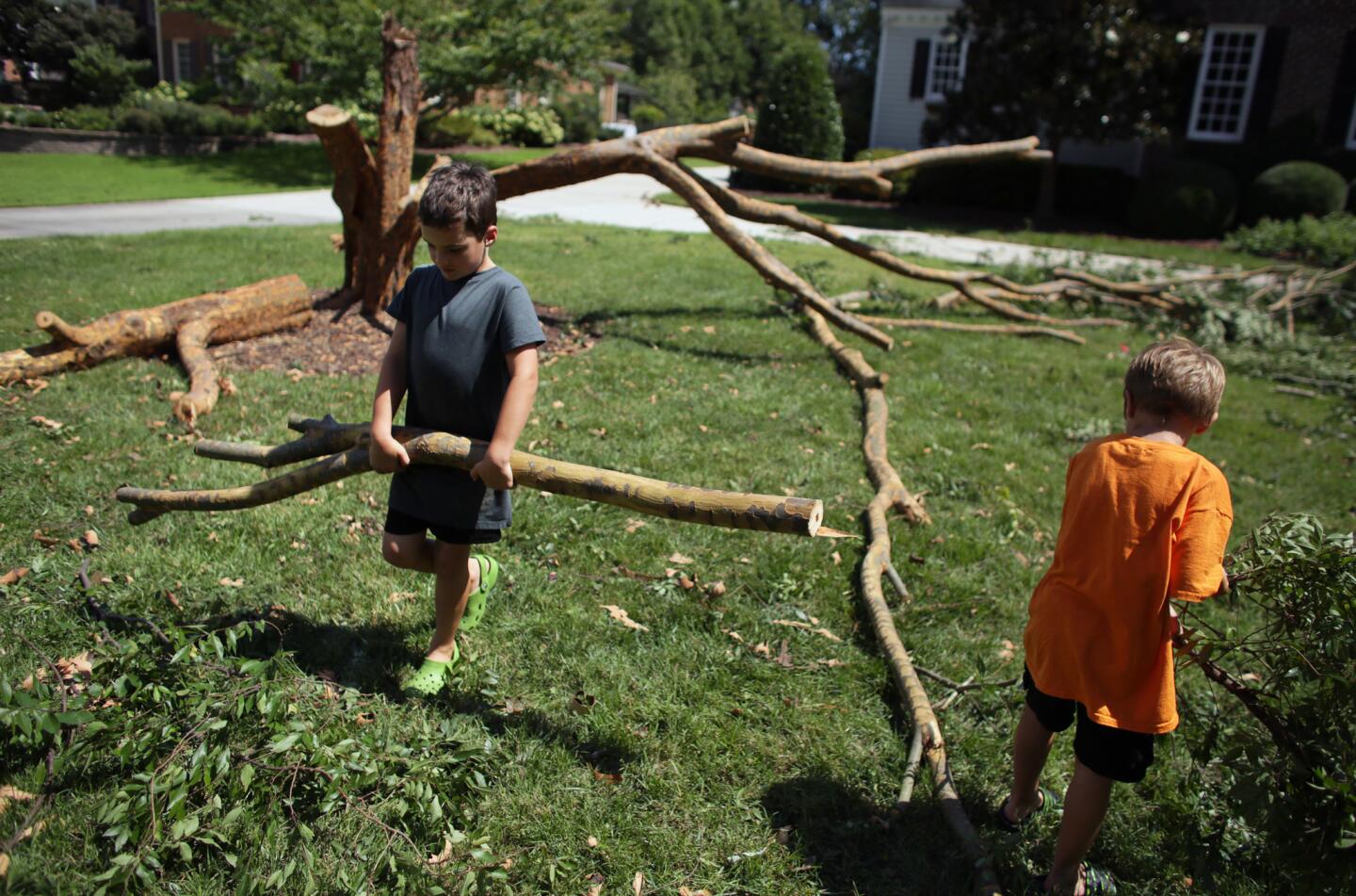 Cormac Worrall, 6, left, helps his father remove tree debris from their yard in Virginia Beach, Va, on Sunday, Sept. 4, 2016.