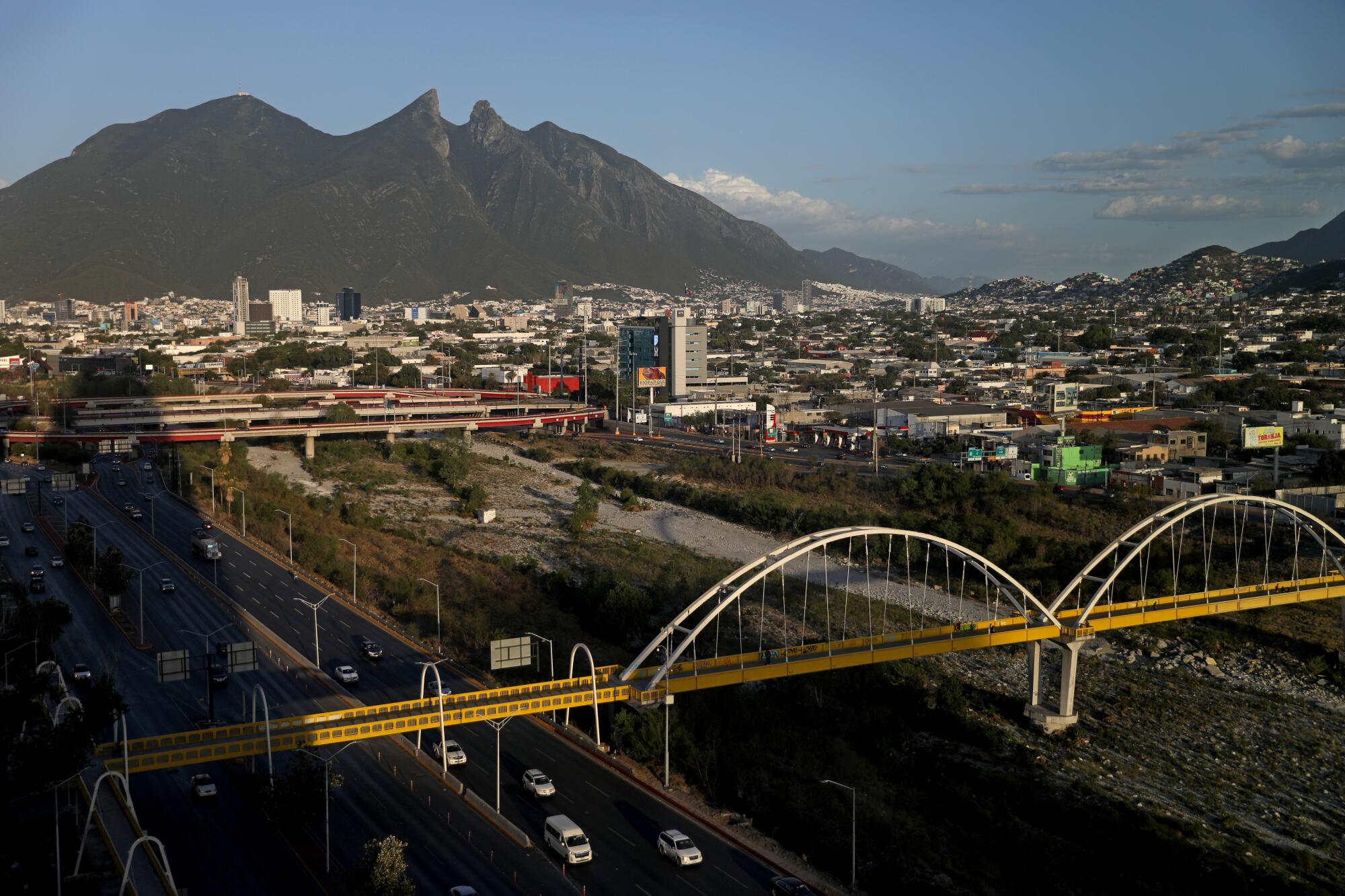 A river runs through a city with a mountain behind it.