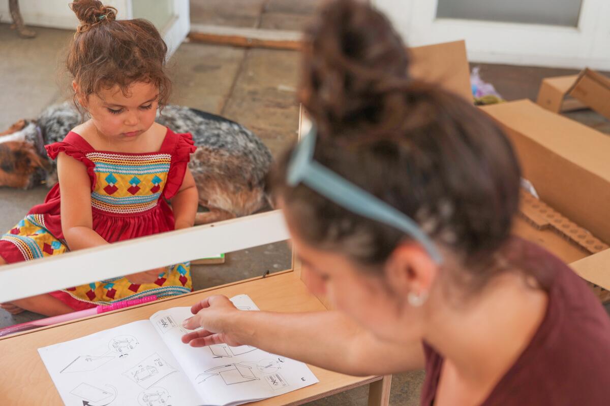 Alyssa Muske, right, looks through directions to build a cabinet as she receives help from Pinon "Pinny" Robbins.