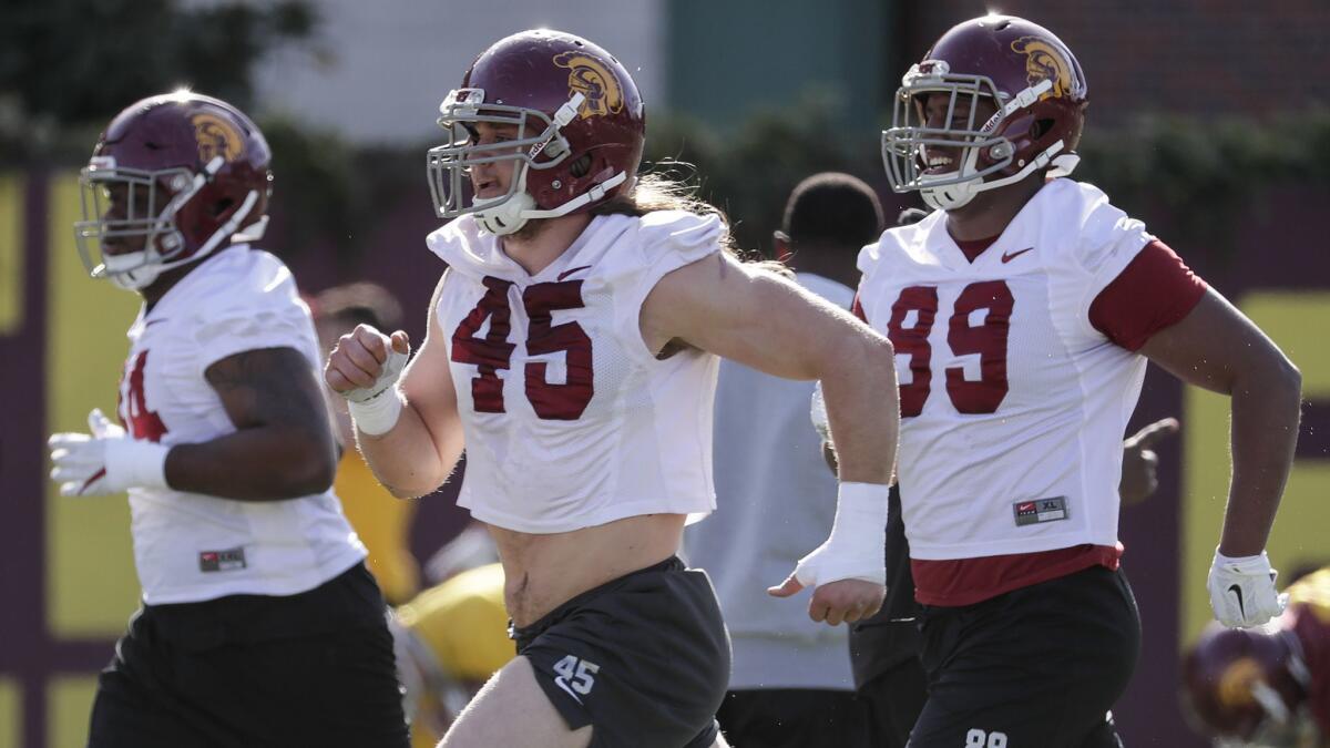 USC linebacker Porter Gustin, 45, and defensive lineman Christian Rector, 89, run to the workout station during spring practice at Howard Jones Field.