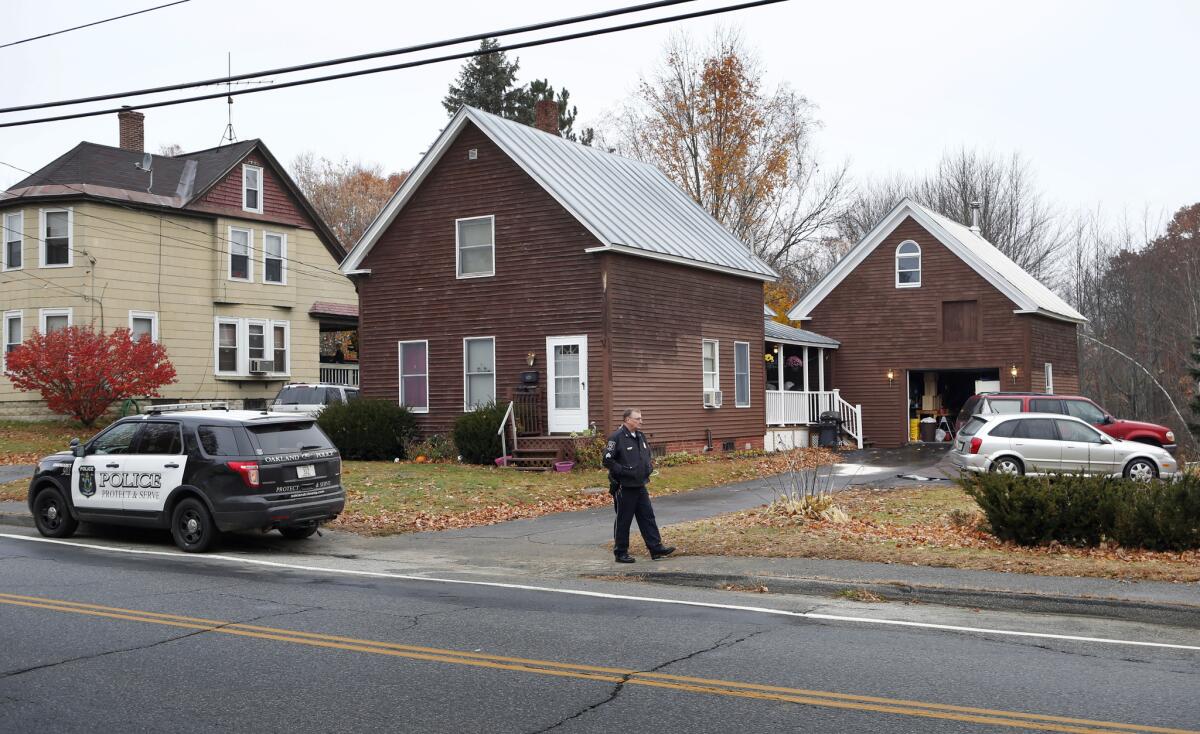 A police officer walks outside a house where two women and a man were shot to death Nov. 5 in Oakland, Maine.