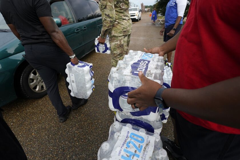 FILE - Volunteers distribute cases of water at a community/fraternal drive-thru water distribution site in Jackson, Miss., Sept. 7, 2022. The NAACP said Tuesday, Sept. 27, that Mississippi is discriminating against Jackson’s majority-Black population by diverting badly needed federal funds for drinking water infrastructure to white communities that needed it less. (AP Photo/Rogelio V. Solis, File)
