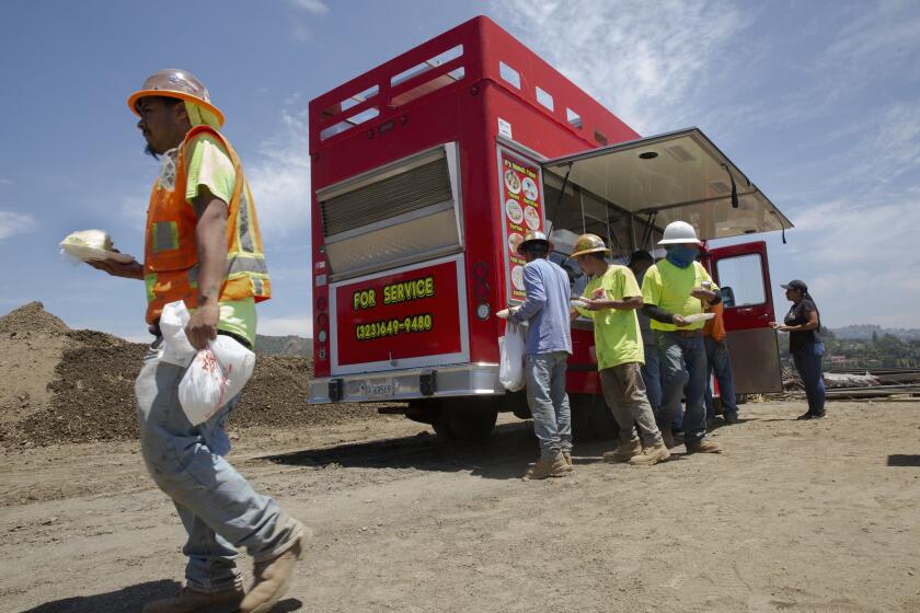 BEL AIR, CALIF. - JULY 19, 2019: Construction workers line up to buy lunch from Jennifer Ramirez, 20, who operates a food truck in Bel Air, Calif. on Friday, July 19, 2019. She is among over a dozen others who operates food trucks for construction workers in Bel Air who otherwise would not have access to purchase food in the neighborhood. (Liz Moughon / Los Angeles Times)