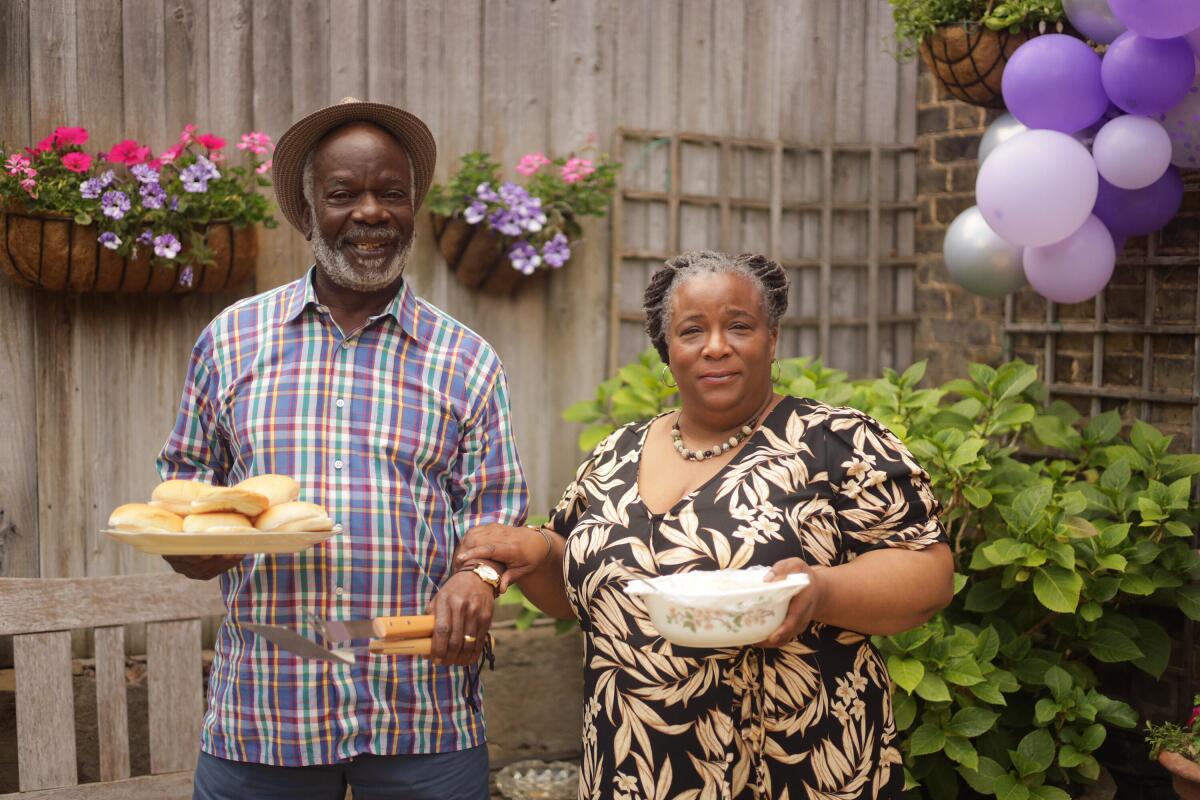 Senior man and woman holding plates of food outdoors.