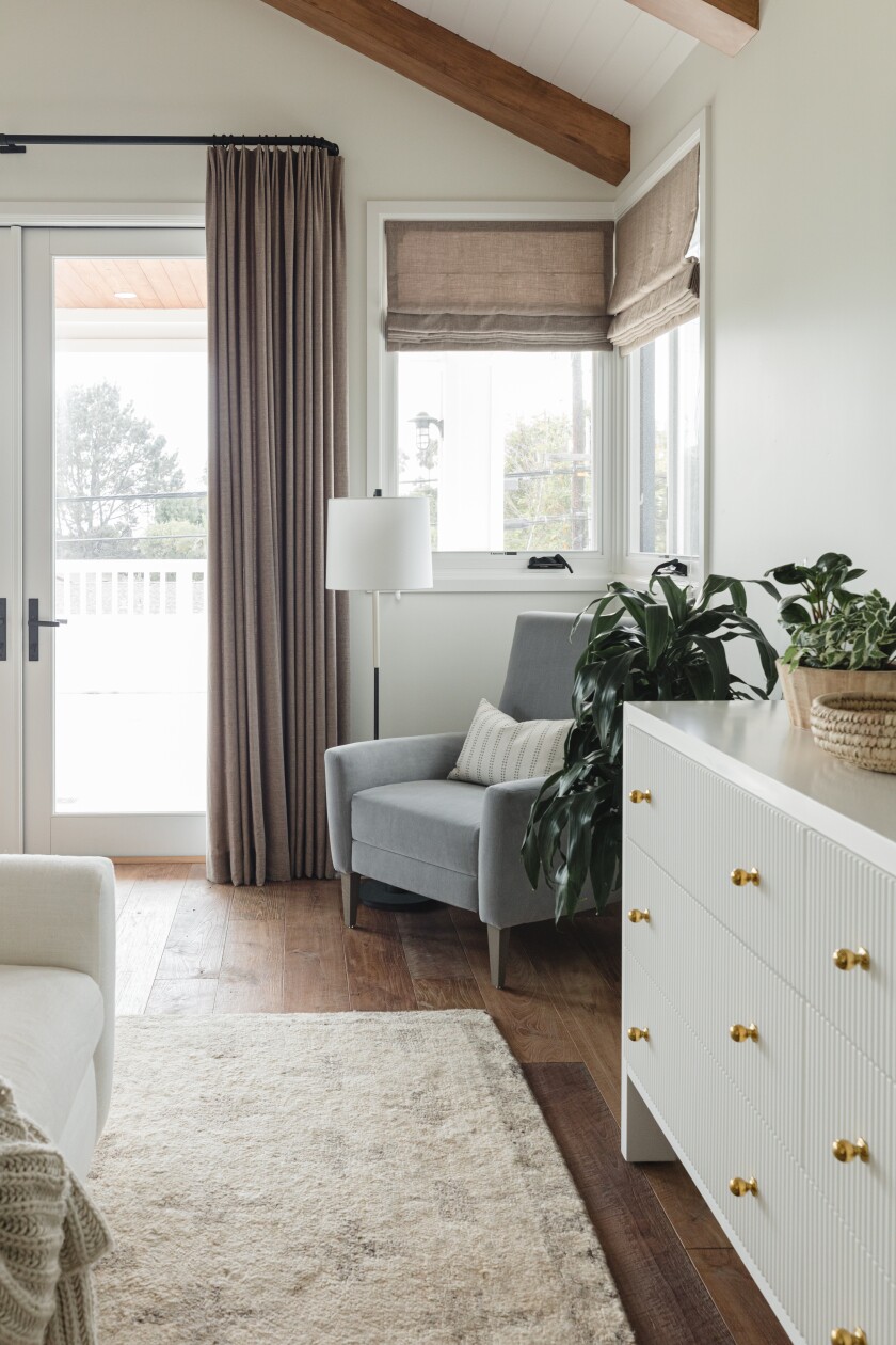 A bedroom has wood floors, with a natural-fiber, midpile area rug under the bed, extending out.