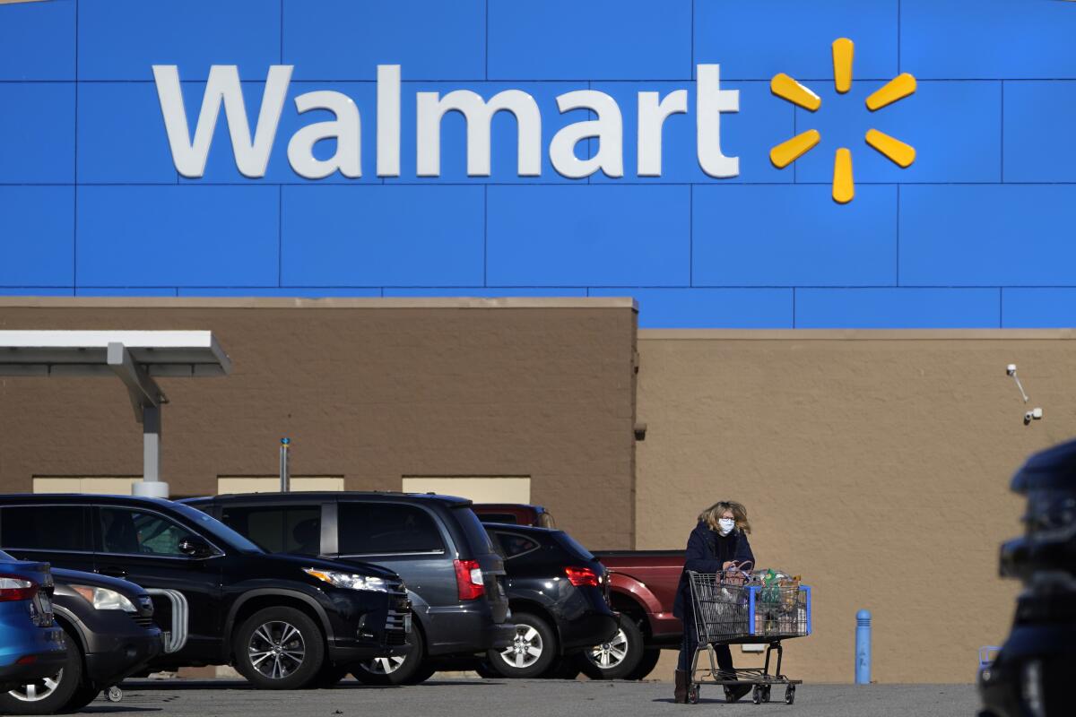 FILE - A woman wheels a cart with her purchases out of a Walmart, on Nov. 18, 2020, in Derry, N.H. Walmart Inc. on Tuesday, Aug. 16, 2022, reported fiscal second-quarter net income of $5.15 billion. The Bentonville, Arkansas-based company said it had profit of $1.88 per share. Earnings, adjusted for non-recurring gains, were $1.77 per share. (AP Photo/Charles Krupa, File)