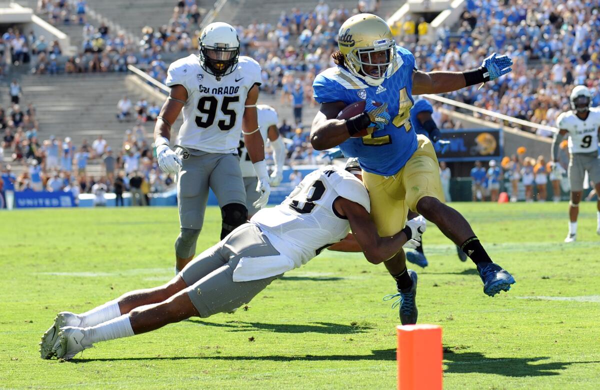 UCLA runnng back Paul Perkins busts through a tackle from Colorado's Phillip Lindsay for a first quarter touchdown at the Rose Bowl on Oct. 31.