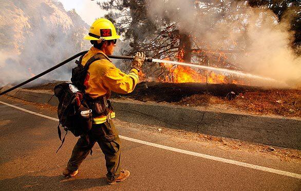 Nolan Hixon shoots water at the flames from Angeles Crest Highway.