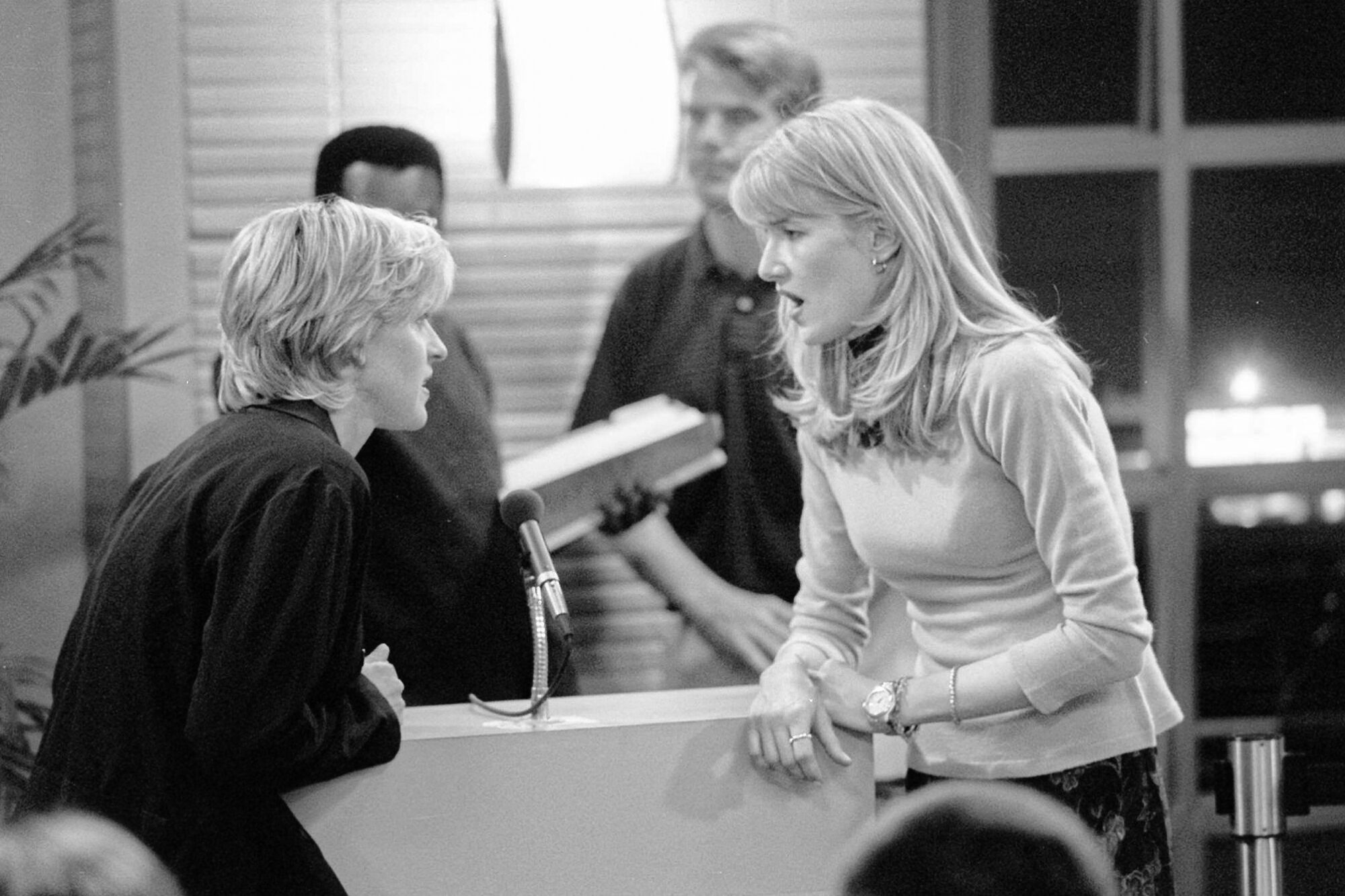 Two women have a conversation over a microphone.