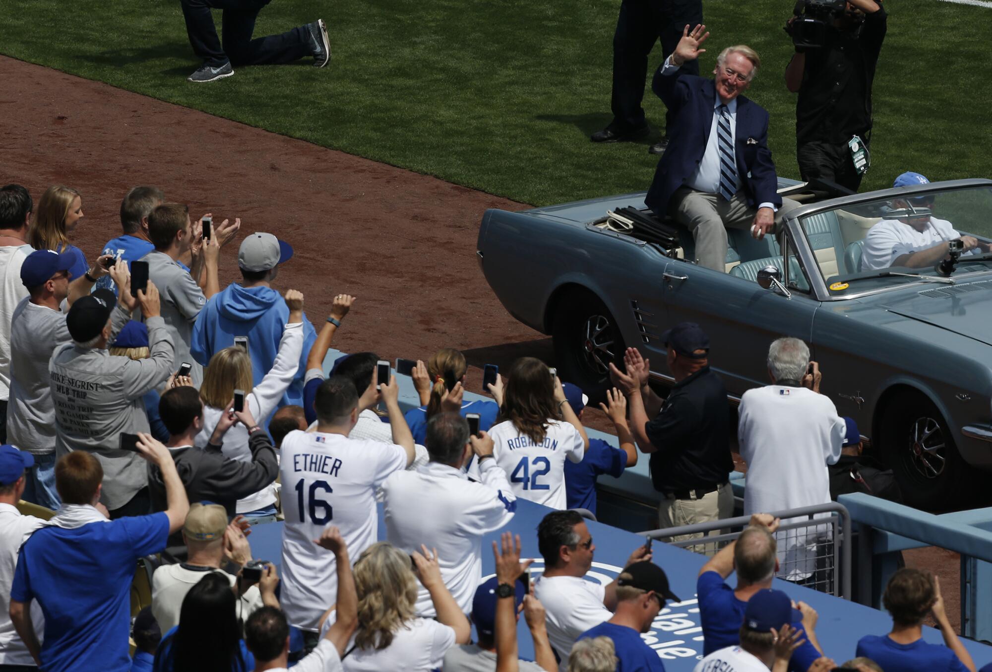 Dodgers announcer Vin Scully waves to fans as he arrives to throw the ceremonial first pitch.