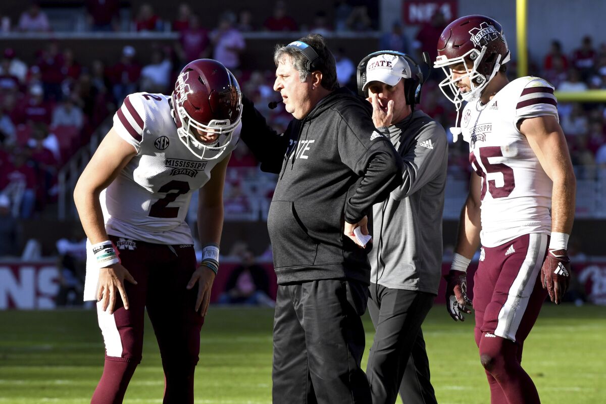 Mississippi State coach Mike Leach, second from left, talks with Will Rogers (2) and Austin Williams (85) during a timeout during the first half of an NCAA college football game against Arkansas, Saturday, Nov. 6, 2021, in Fayetteville, Ark. (AP Photo/Michael Woods)