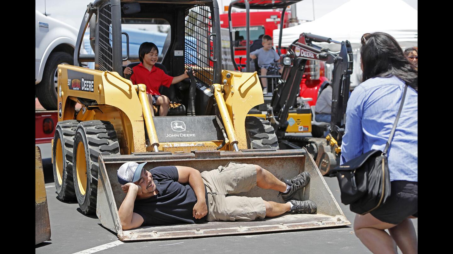 Janice Coscolluela, right, of Los Angeles takes a picture of her husband Robert, bottom, and son Markus, 3, top, in a John Deere bulldozer during Truck Adventures at the OC Fair & Event Center in Costa Mesa on Saturday, June 16.