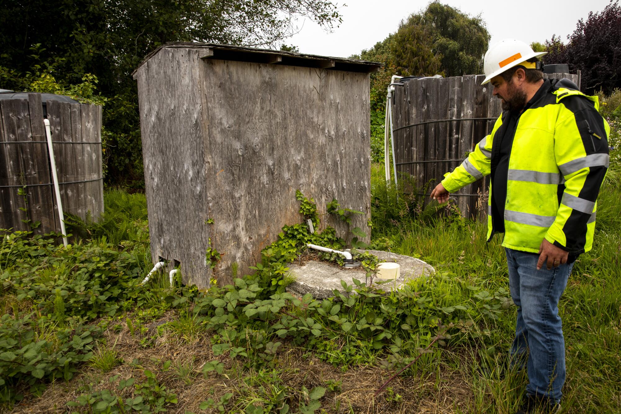 A man in a hard hat points to a well.