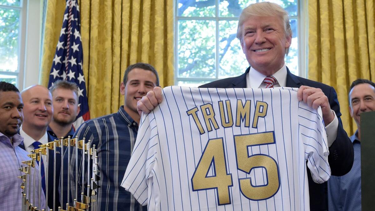 President Donald Trump holds up a baseball jersey on June 28, in the Oval Office of the White House in Washington.