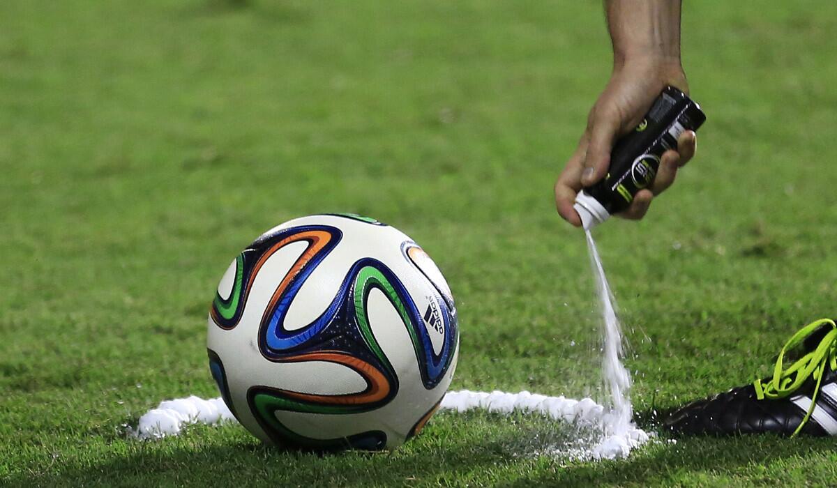 A World Cup referee uses vanishing spray to mark the spot for a free kick.