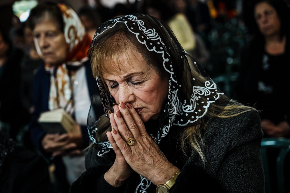 A woman in a head covering prays.