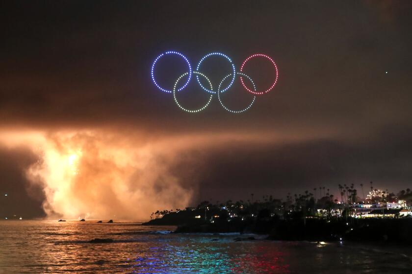 A group of drones makes the shape of the Olympic rings as part of the Fourth of July drone show over Main Beach Park in Laguna Beach on Thursday July 4th. This year the city tried out a drone show in lieu of its traditional fireworks in the evening. Traditiona fireworks from Emerald Bay can be seen in background.