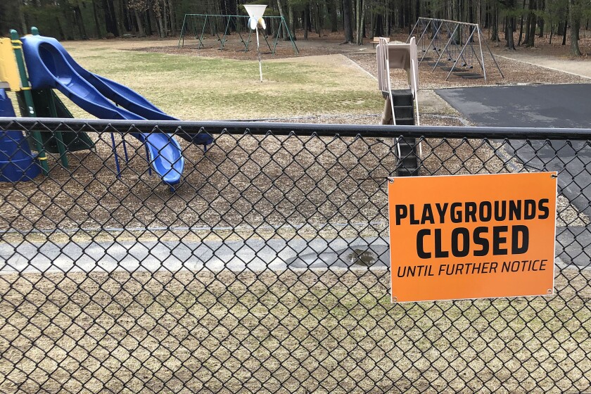 FILE - This Friday, March 20, 2020 file photo shows a closed sign near an entrance to a playground at an elementary school in Walpole, Mass., amid the COVID-19 coronavirus outbreak. Child welfare agencies in the U.S. have a difficult mission in the best of times, and now they're scrambling to confront new challenges during the coronavirus outbreak. (AP Photo/Steven Senne)