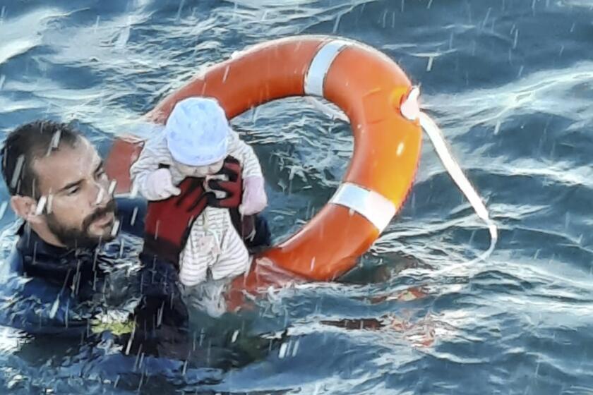 In this photo provided by the Spanish Civil Guard in Ceuta, Spain, on Tuesday May, 18, 2021, a member of the civil guard rescues a baby that was separated from its parents, who were migrants, in the sea off Ceuta, Spain. Spain's North African enclave of Ceuta is facing a humanitarian crisis after thousands of migrants swum around or jumped a border fence left unguarded by Morocco as part of a diplomatic row with its European neighbor. (Guardia Civil via AP)