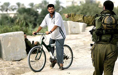 An Israeli soldier motions for a Palestinian to get off his bike and give a wide berth away from the Shirat HaYam settlement. Jewish settlers in the beachfront enclave of Shirat HaYam wait anxiously for the Israeli Defense Forces to arrive, bringing their orders to vacate the Gaza land they have occupied for decades. Trouble in the neighboring settlement of Neve Dekalim may have brought them a temporary reprieve as soldiers were occupied there and could not deliver the papers in the morning as they had planned.