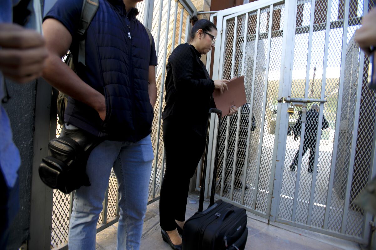On Tuesday, December 10, 2019 standing on the Mexico side of the border at the PedWest U.S. port of entry in San Ysidro, Margaret Cargioli (r), managing attorney for Immigrant Defenders Law Center in San Diego waits with Jose, 20 (left) to speak with a CBP supervisor. Cargioli and Jose were allowed to cross into the U.S. According to Cargioli, she an her Jose earlier tried to cross legally at the San Ysidro port of entry on December 6th with all the necessary paperwork including the required 9k immigration bond, but was denied entry.