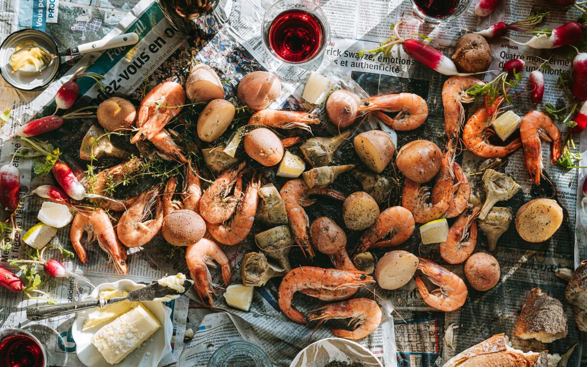 Shrimp, potatoes and artichokes on a table lined with newsprint