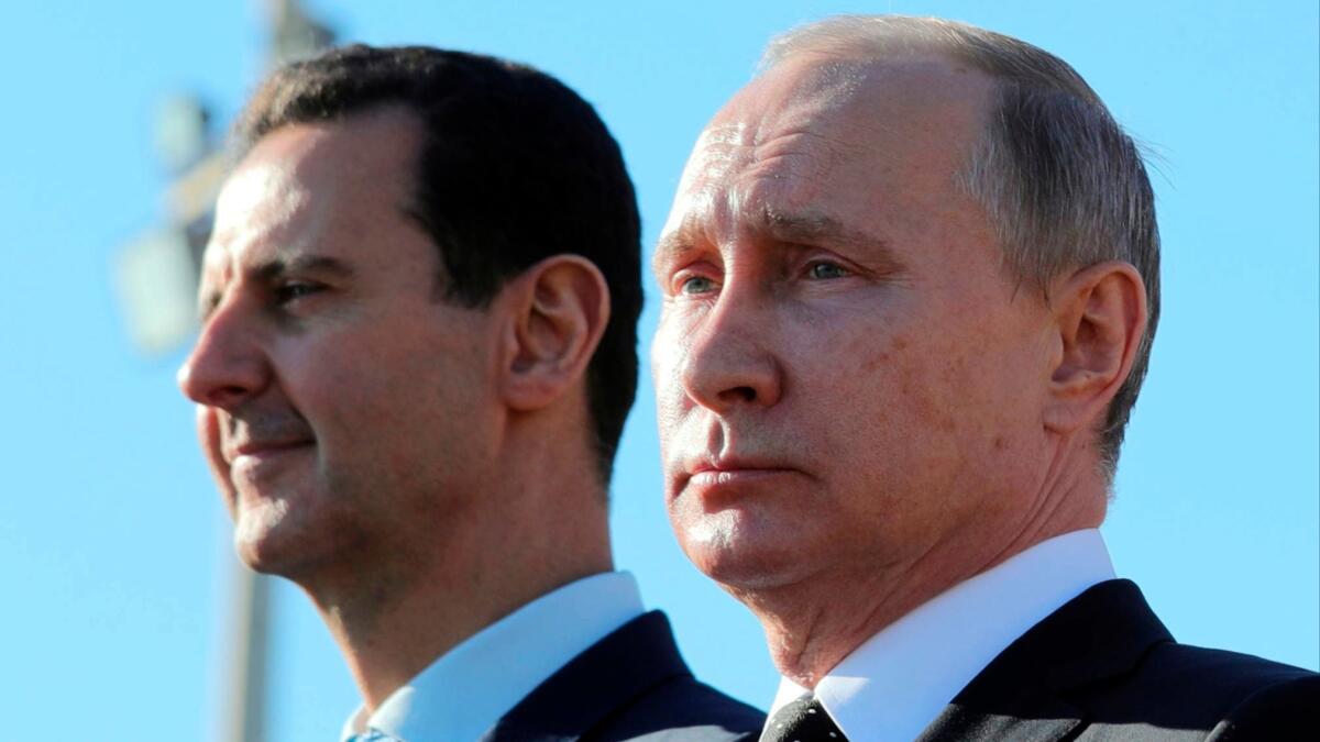 Russian President Vladimir Putin, right, and Syrian President Bashar Assad in December watch the troops marching at the Hemeimeem air base in Syria. Putin's government denies Russian mercenaries killed in Syria worked on behalf of Russia.