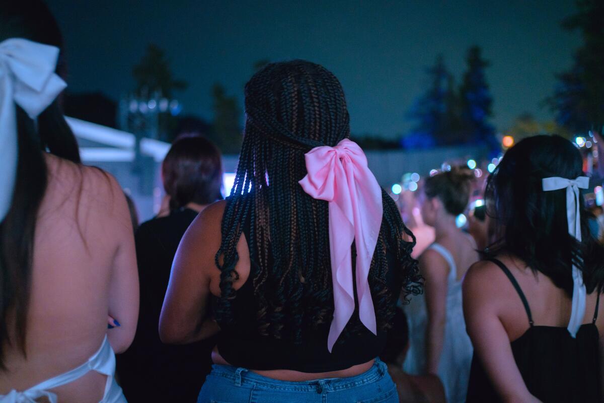 Fans sporting hair ribbons watch Gracie Abrams' concert at the Greek Theatre on Monday.