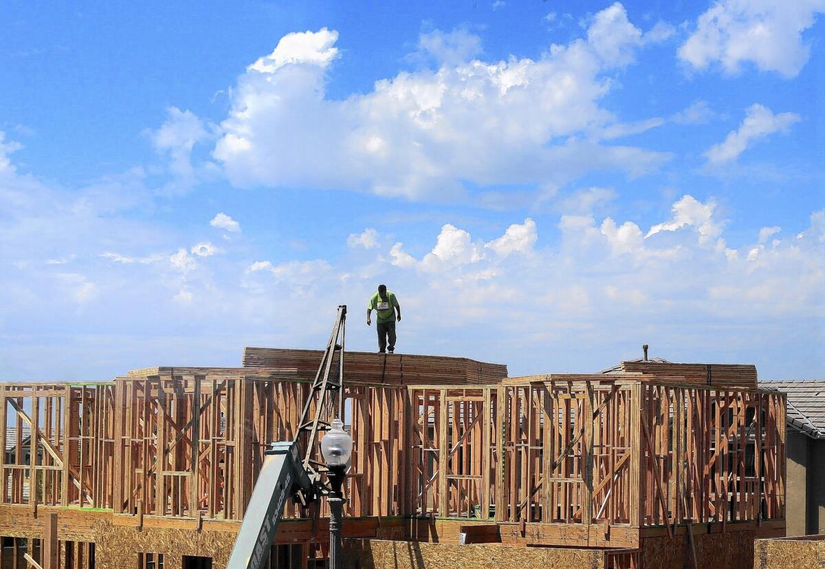 A framer works on the roof line of a new home under construction Tuesday at the William Lyon Homes site in the Pavilion Park development in Irvine.