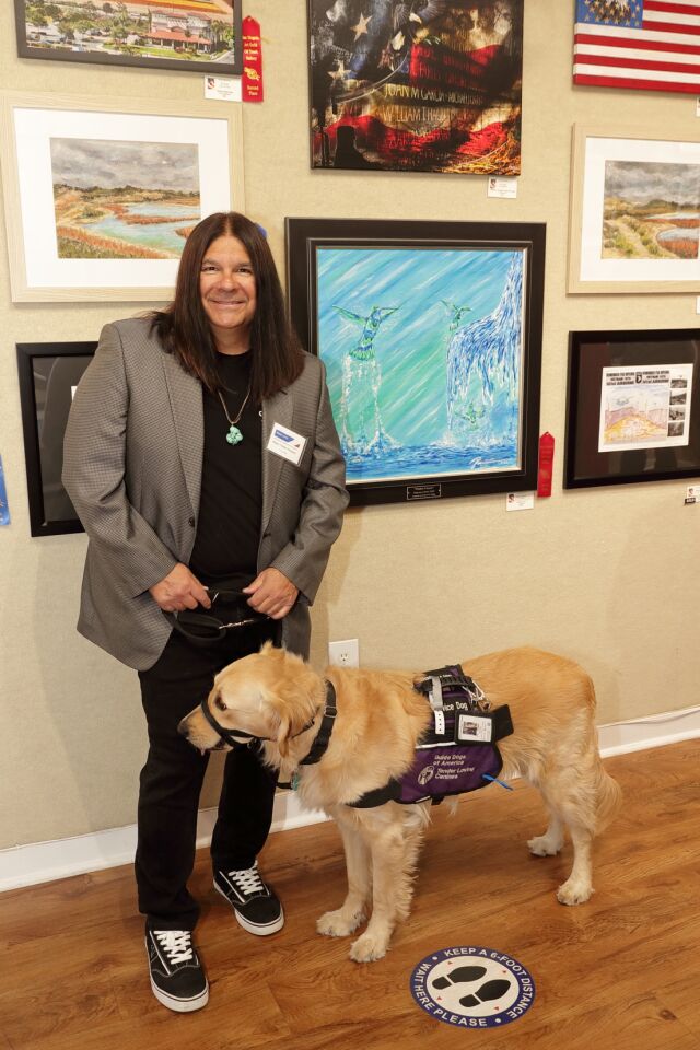 Artist Ruben "Chato" Hinojosa, Jr. and his dog Simba with his painting "Father's Love"