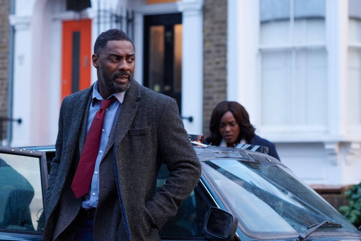 Idris Elba and Wunmi Mosaku get out of a car in front of a house