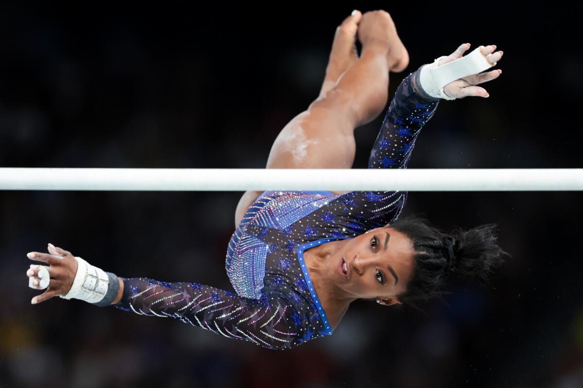 Simone Biles in midflight while performing on the uneven bars 