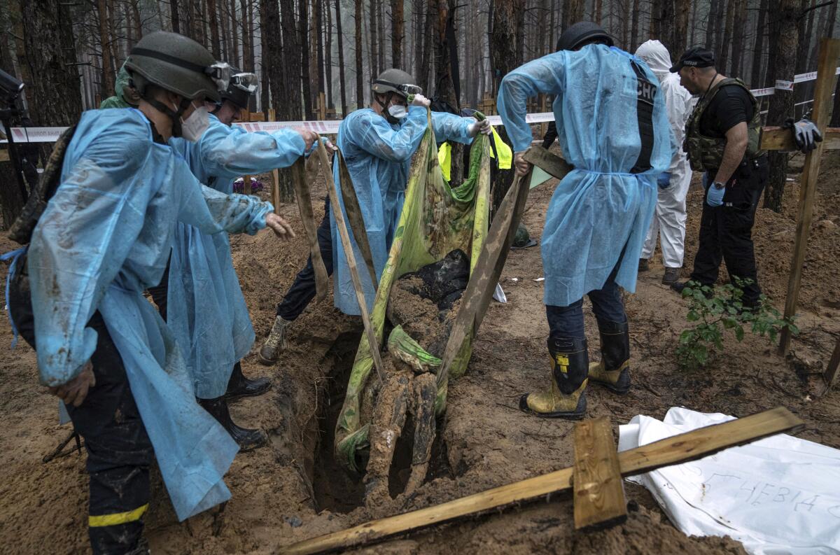 Workers lifting a dirt-covered body from a hole in the ground.