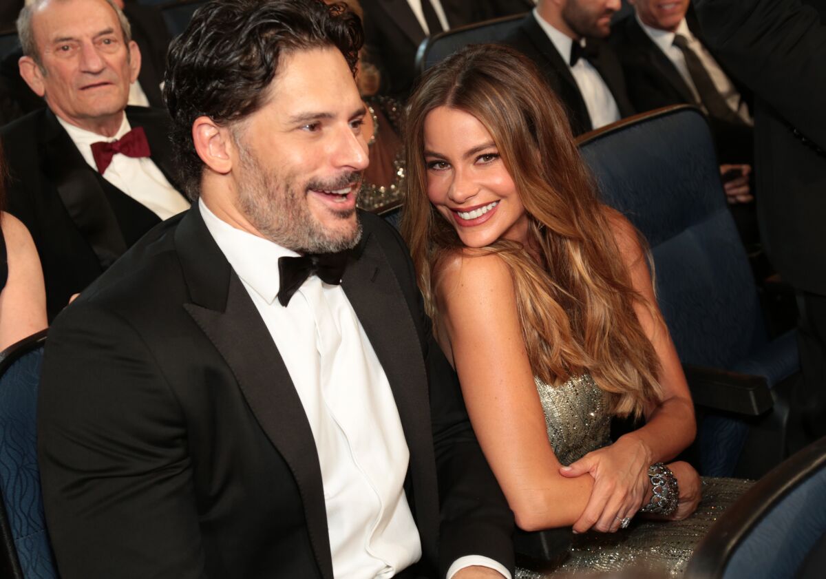 Joe Manganiello wears a tux and smiles, next to his wife Sofia Vergara who wears a sequin gown and smiles.