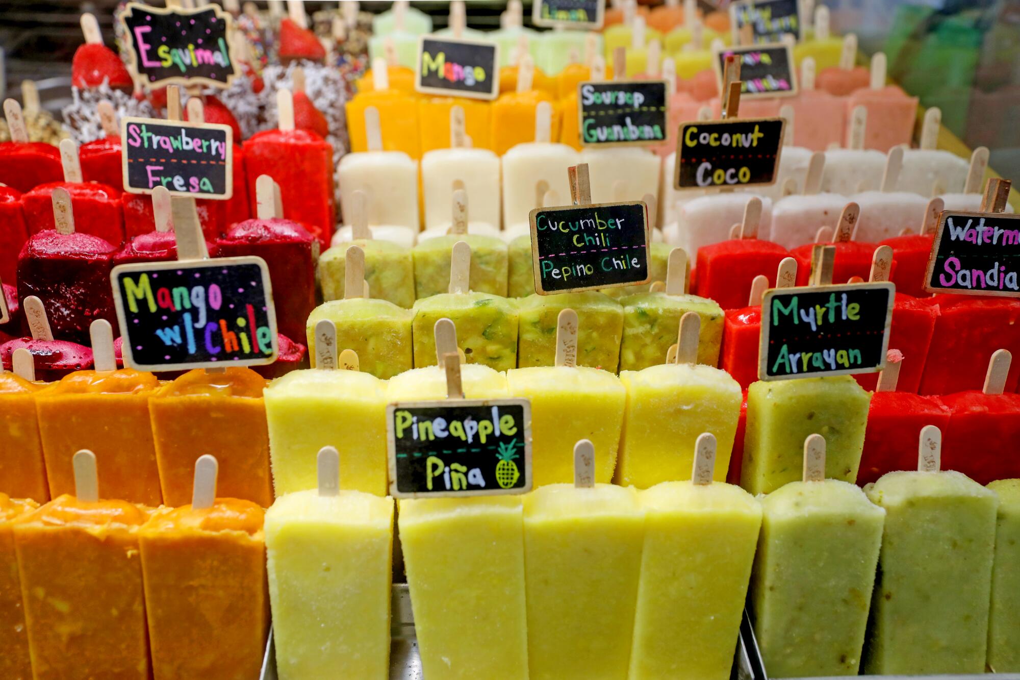 A display case of multicolored frozen popsicles, or paletas. 