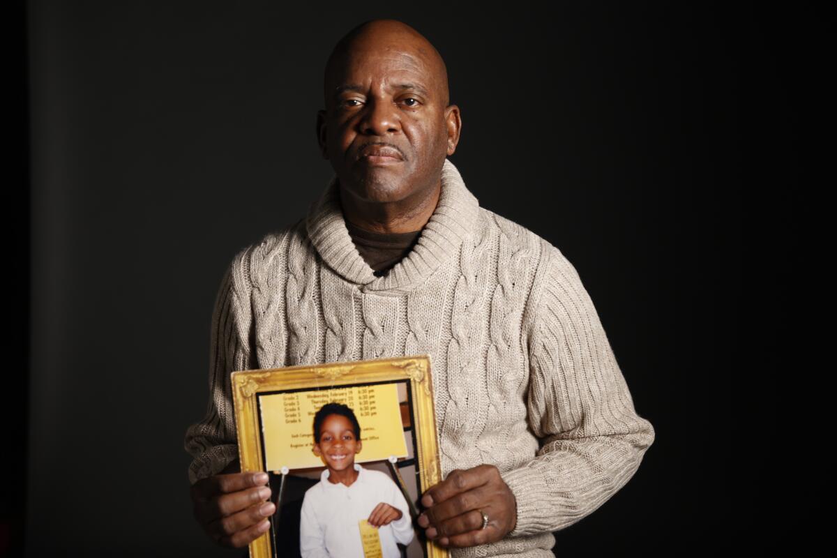 Ruett Foster holds a photo of his 7-year-old son, who was killed by gunfire.