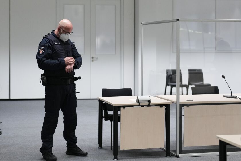 A judicial officer looks at his watch prior to a trail against a 96-year-old former secretary for the SS commander of the Stutthof concentration camp at the court room in Itzehoe, Germany, Thursday, Sept. 30, 2021. The woman who is charged of more than 11,000 counts of accessory to murder has not appeared and is wanted by warrant. (AP Photo/Markus Schreiber, Pool)