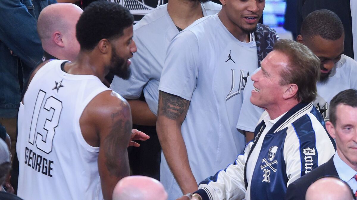 Paul George, left, and Arnold Schwarzenegger shake hand at the NBA All-Star Game.
