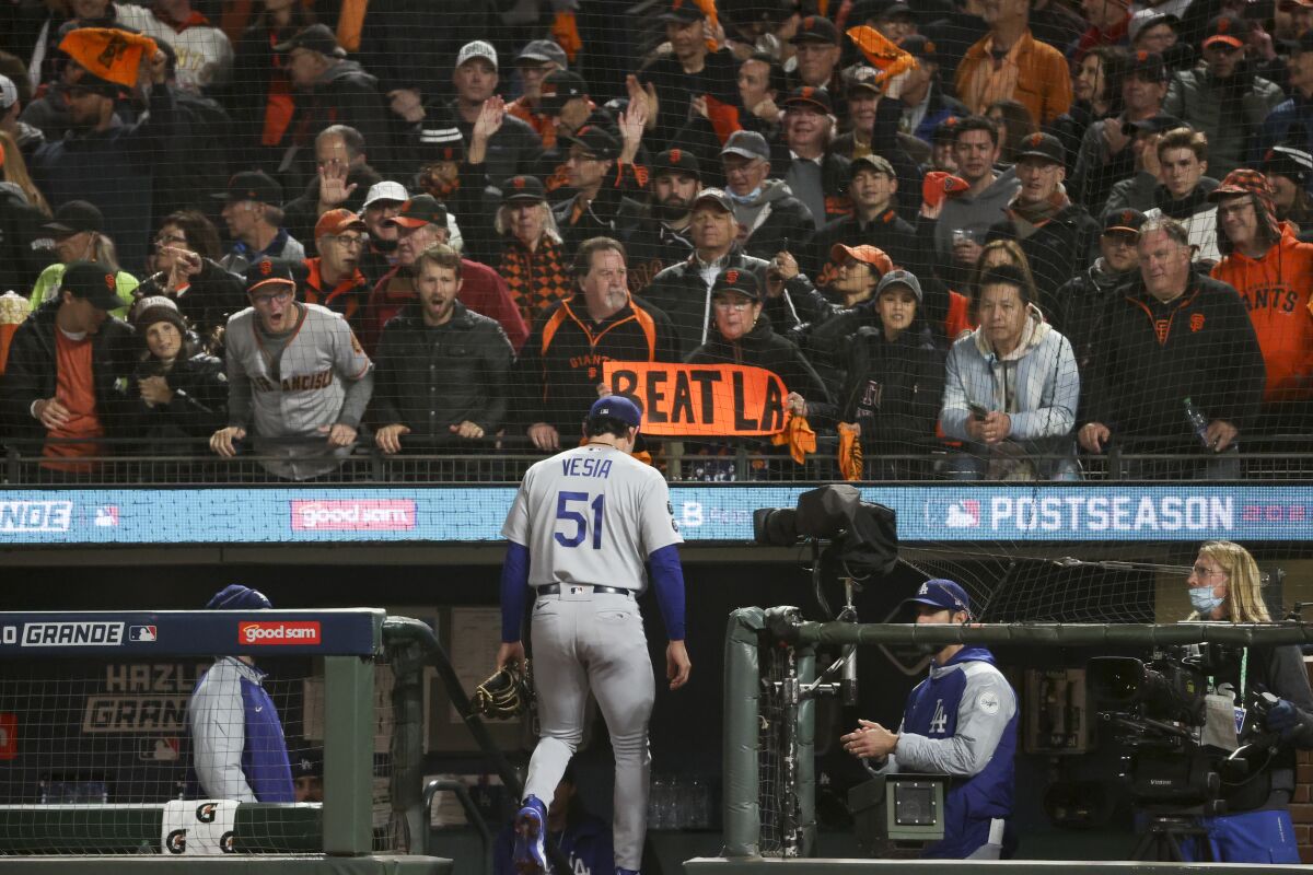 San Francisco Giants fans hold signs and taunt L.A. Dodgers reliever Alex Vesia as he leaves a game